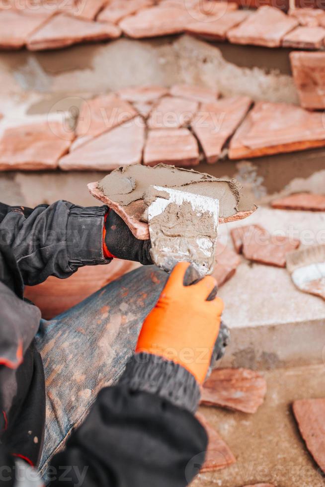 posa di piastrelle ricce su colla - imitazione della pietra naturale - di fronte alla casa dall'esterno foto