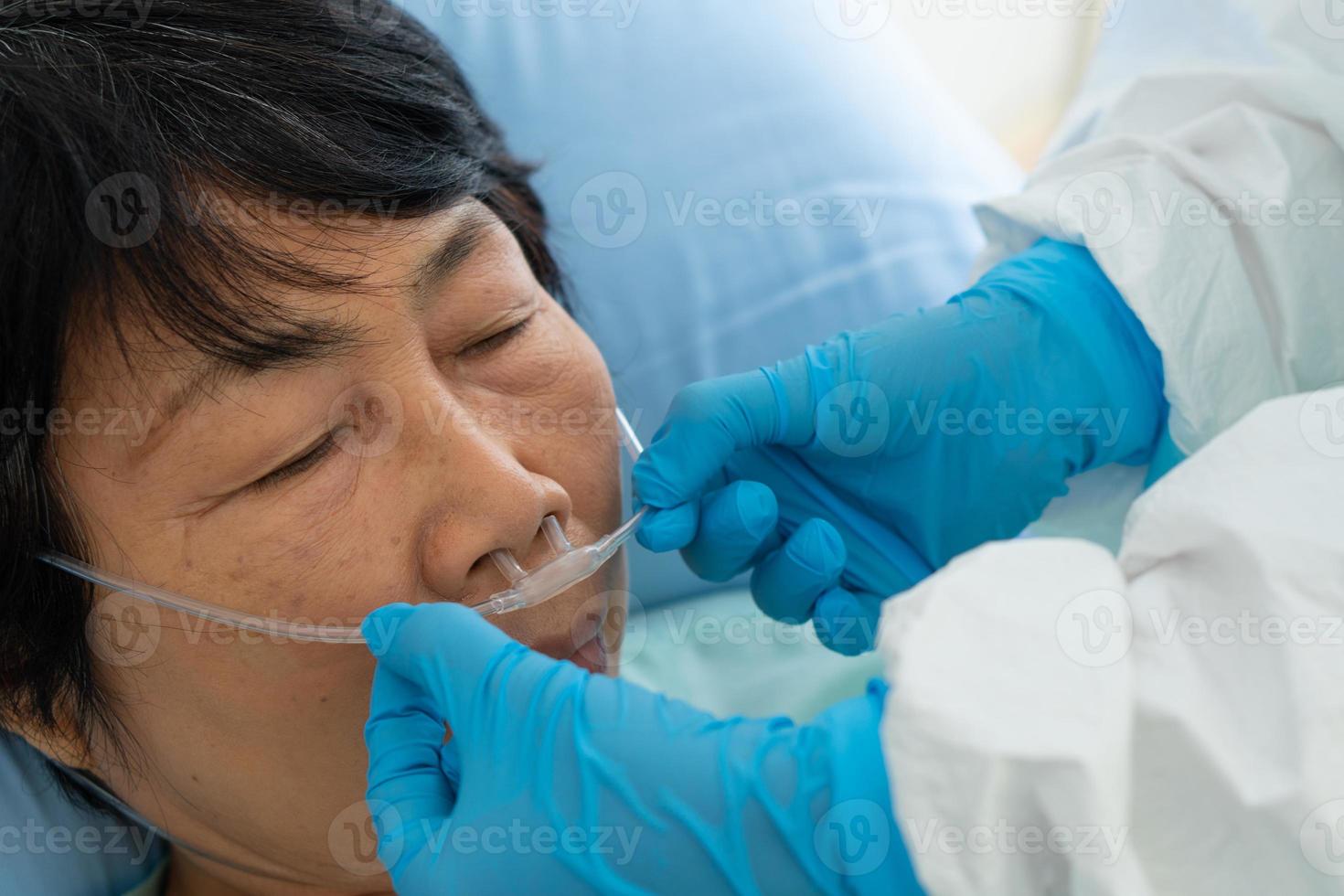 medici in dispositivi di protezione individuale o dpi che somministrano cannula di ossigeno alla paziente asiatica con infezione da covid-19 o coronavirus in unità di isolamento in ospedale durante la pandemia. concetto medico foto