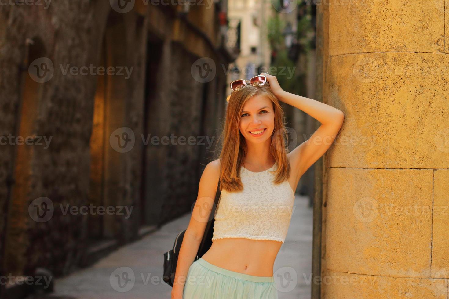 giovane donna sorridente che cammina per le strade di barcellona, sfondo di pietra, scatto rumoroso, ora del tramonto foto