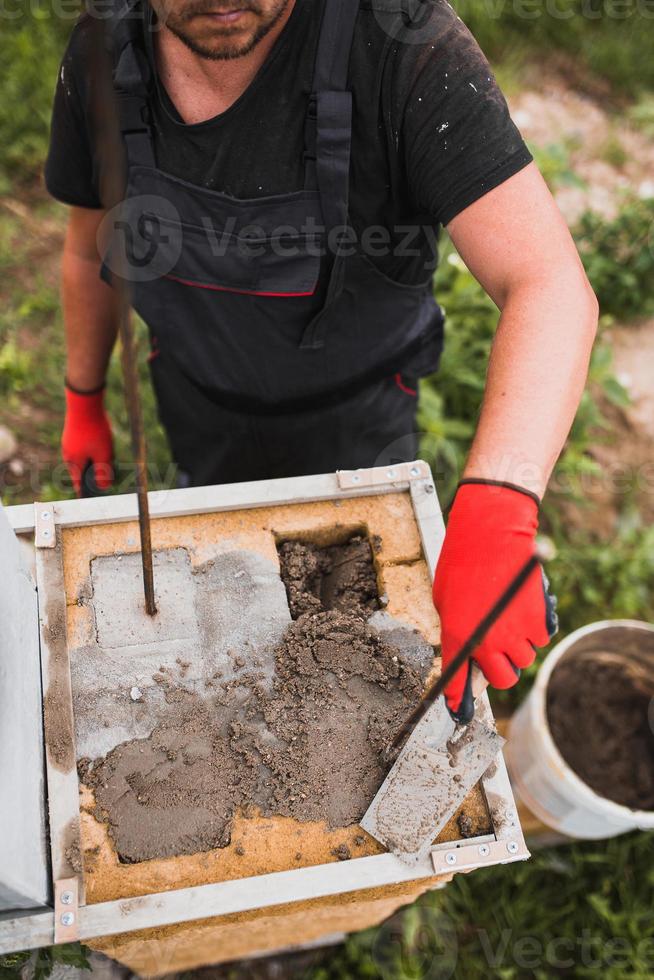 adesivo cementizio per muratura in blocchi di pietra e mattoni in edilizia - un muratore professionista al lavoro foto