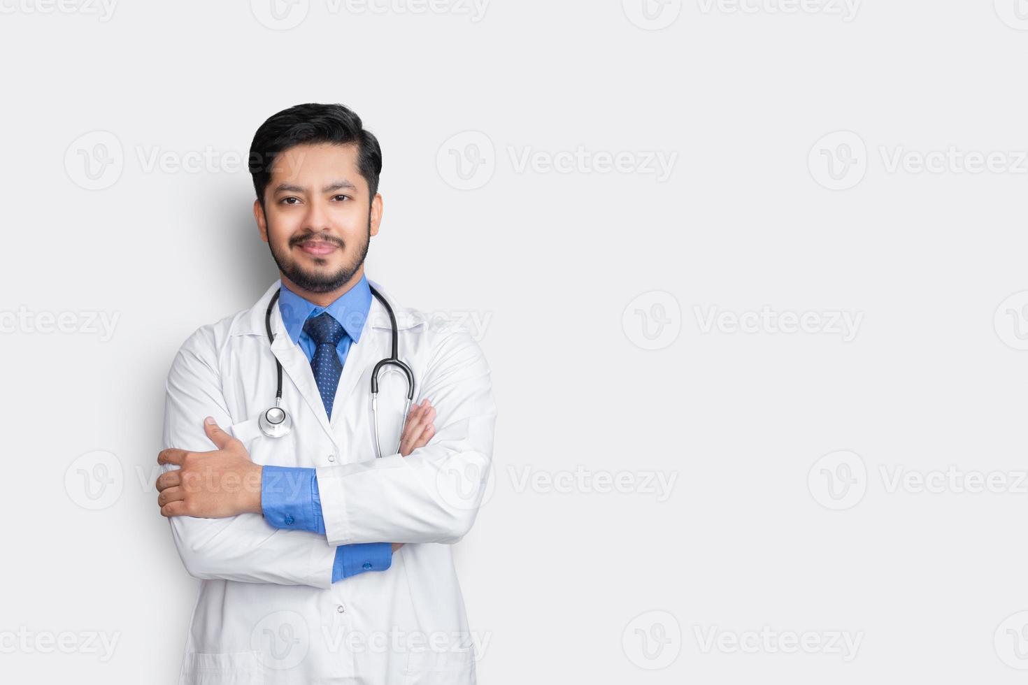 ritratto di medico maschio con stetoscopio e croce braccio isolato su sfondo bianco. concetto di assicurazione sanitaria. foto