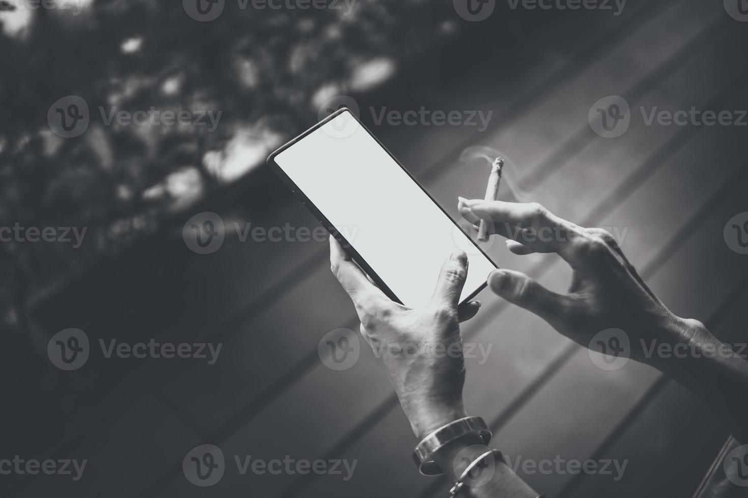 le mani e lo smartphone della donna con le sigarette. foto