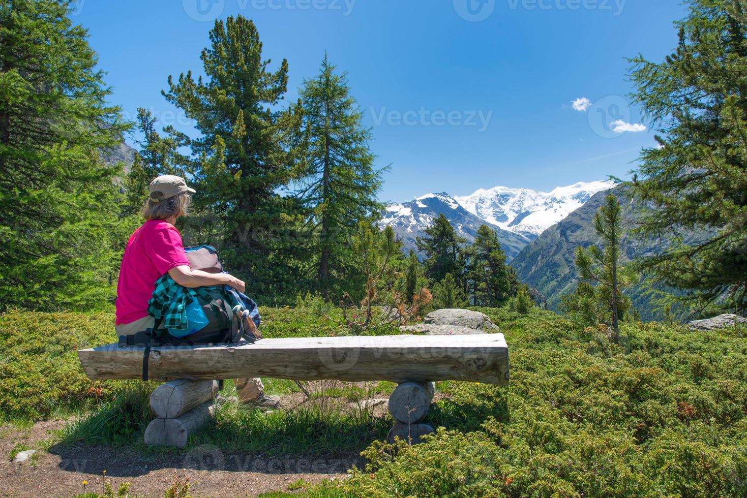 una donna anziana si riposa durante un trekking alpino foto