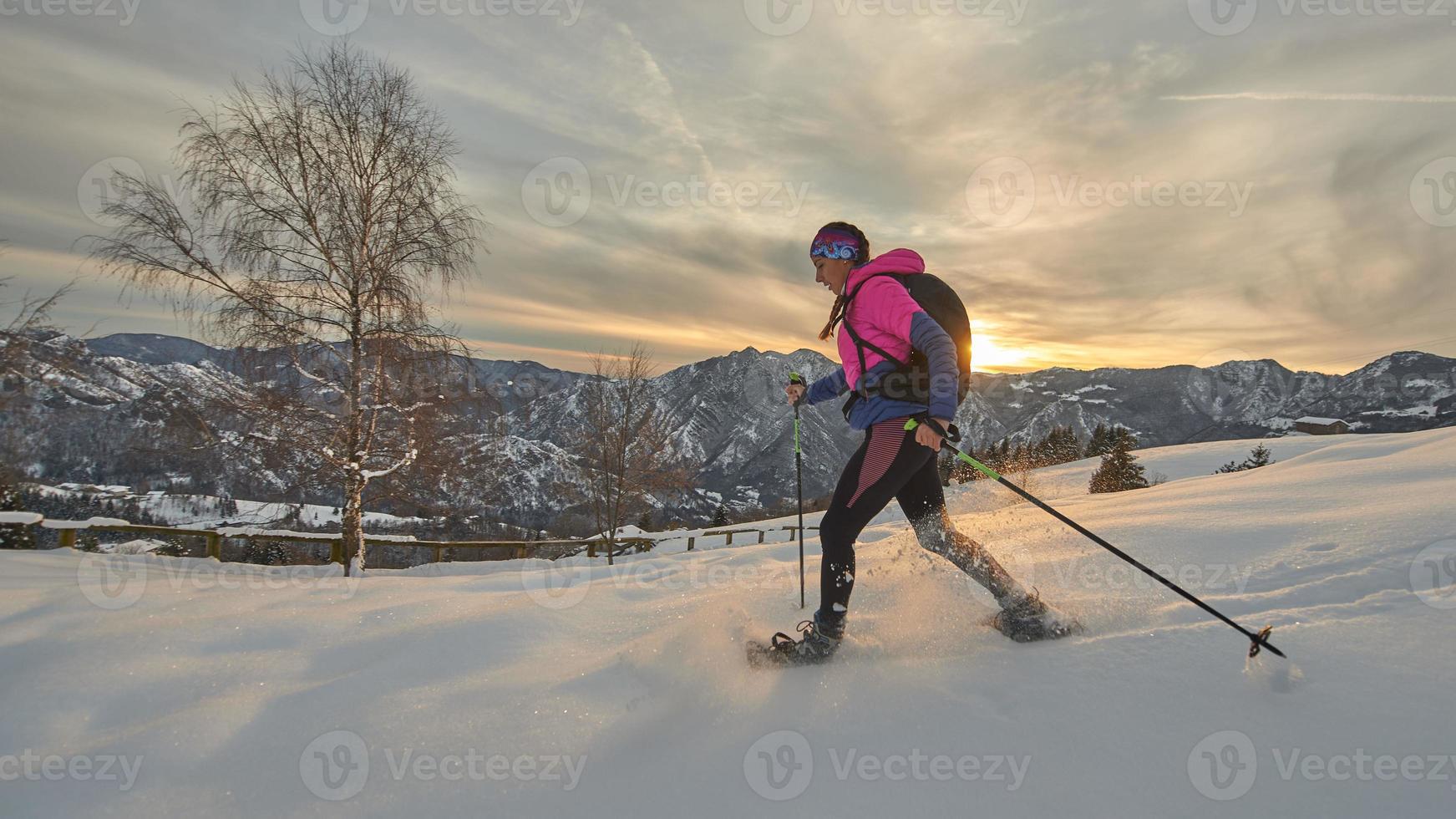 una ragazza con le ciaspole in un bellissimo tramonto invernale foto