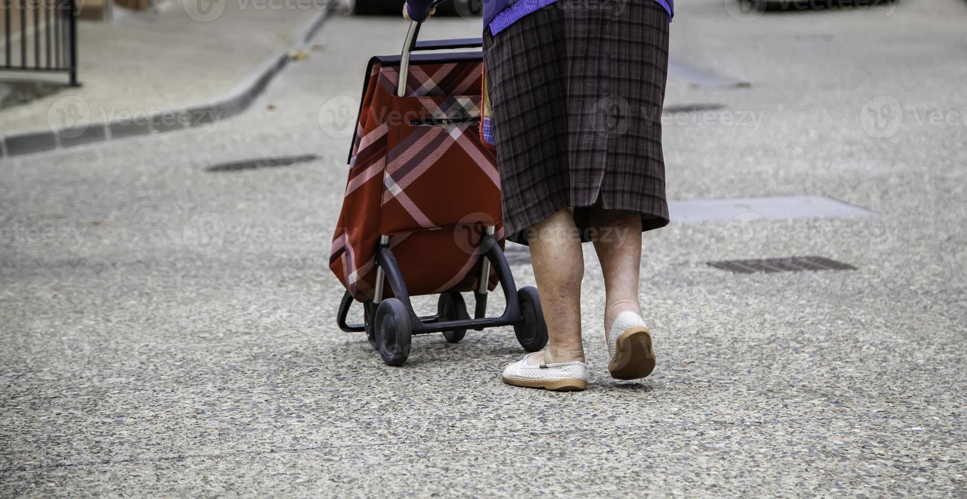 donna anziana con carrello della spesa foto