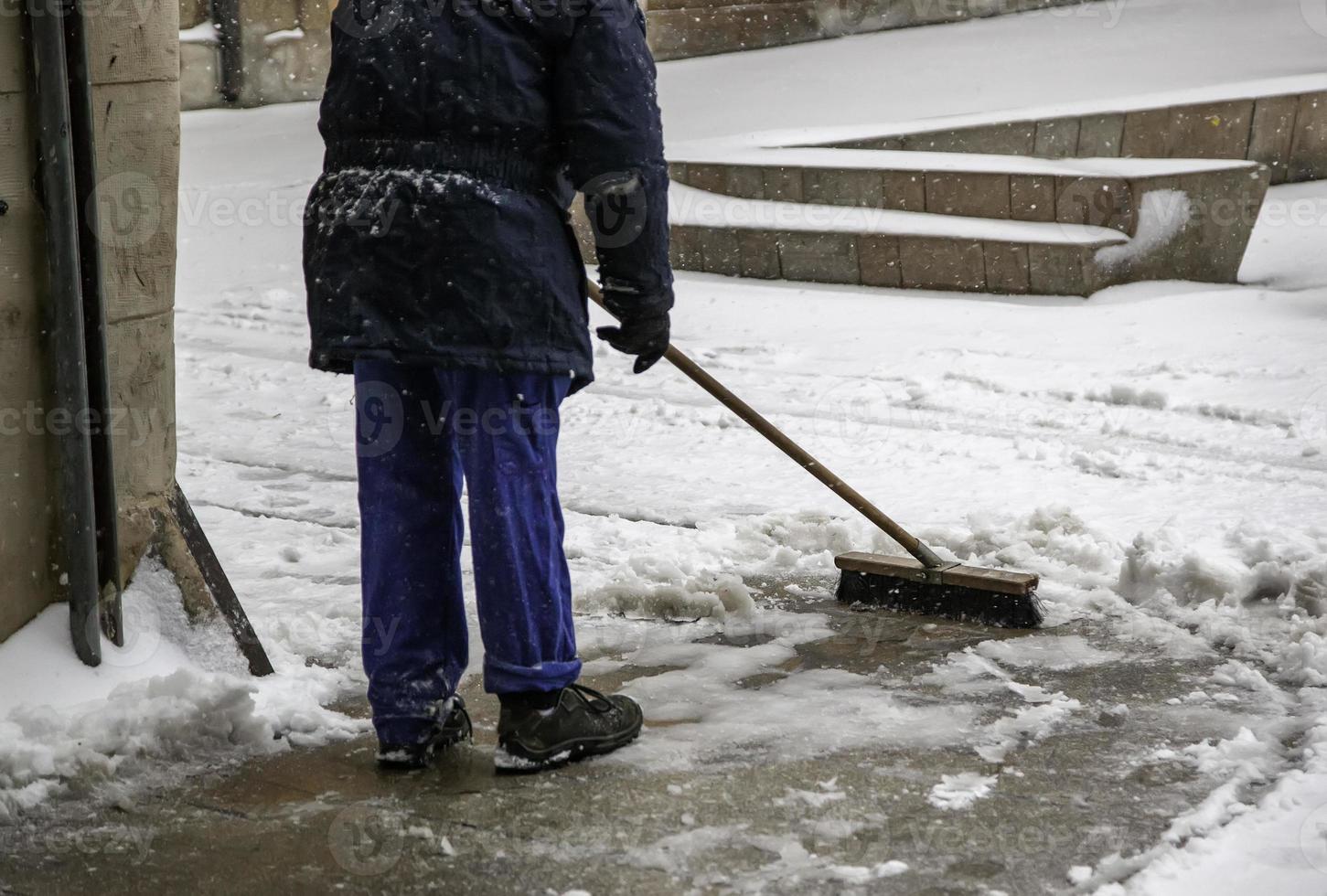 persona che spazza una strada innevata foto