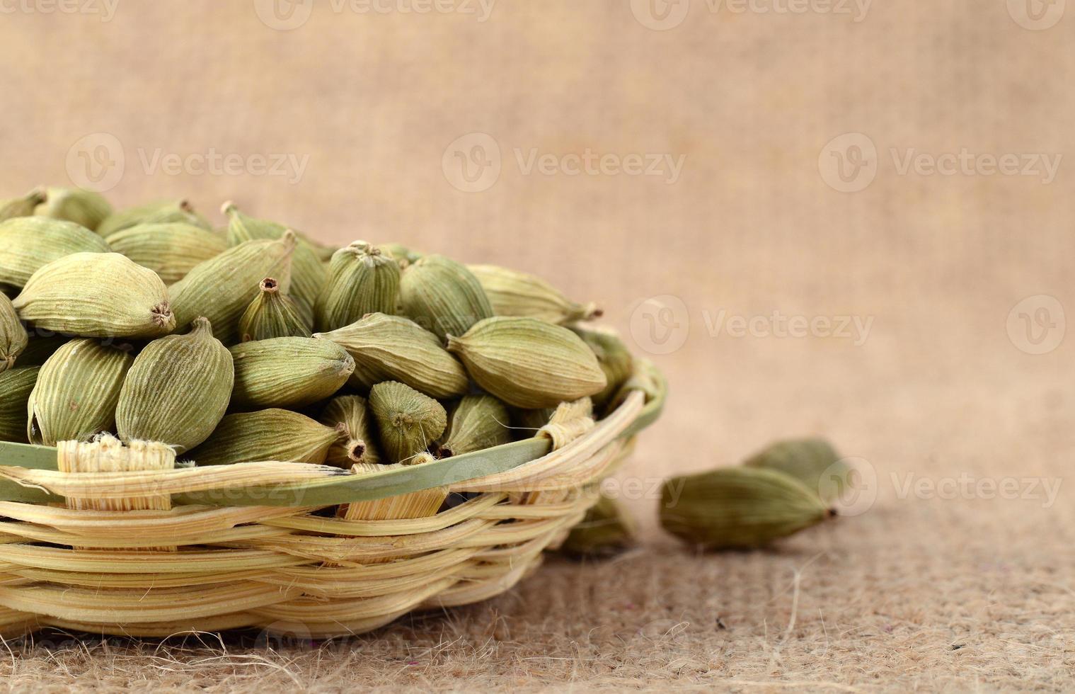 baccelli di cardamomo verde in cesto di bambù su tela di sacco foto