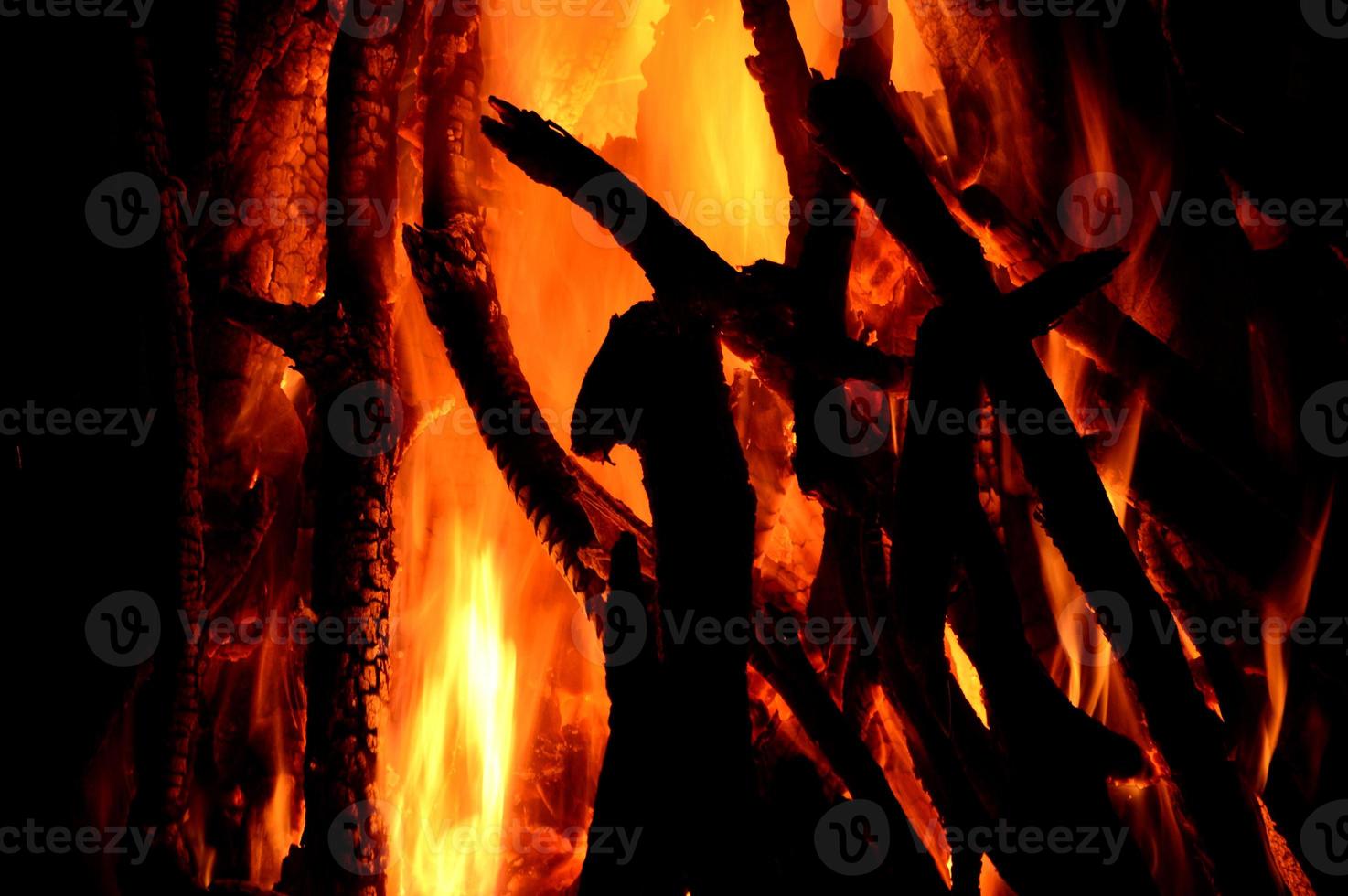primo piano di tronchi che bruciano nel camino su sfondo nero foto
