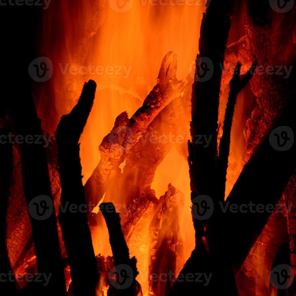 primo piano di tronchi che bruciano nel camino su sfondo nero foto