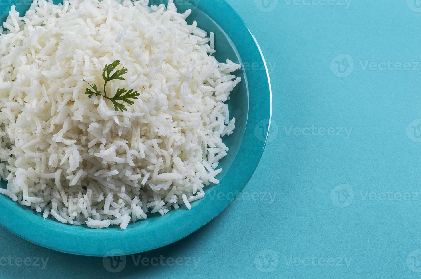 riso basmati bianco cotto cotto con coriandolo in un piatto blu su sfondo blu foto