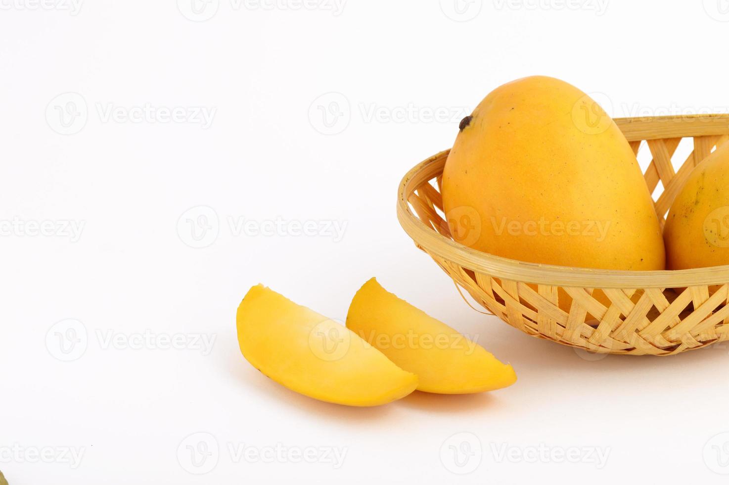 Frutto di mango in cesto con fetta su sfondo bianco foto