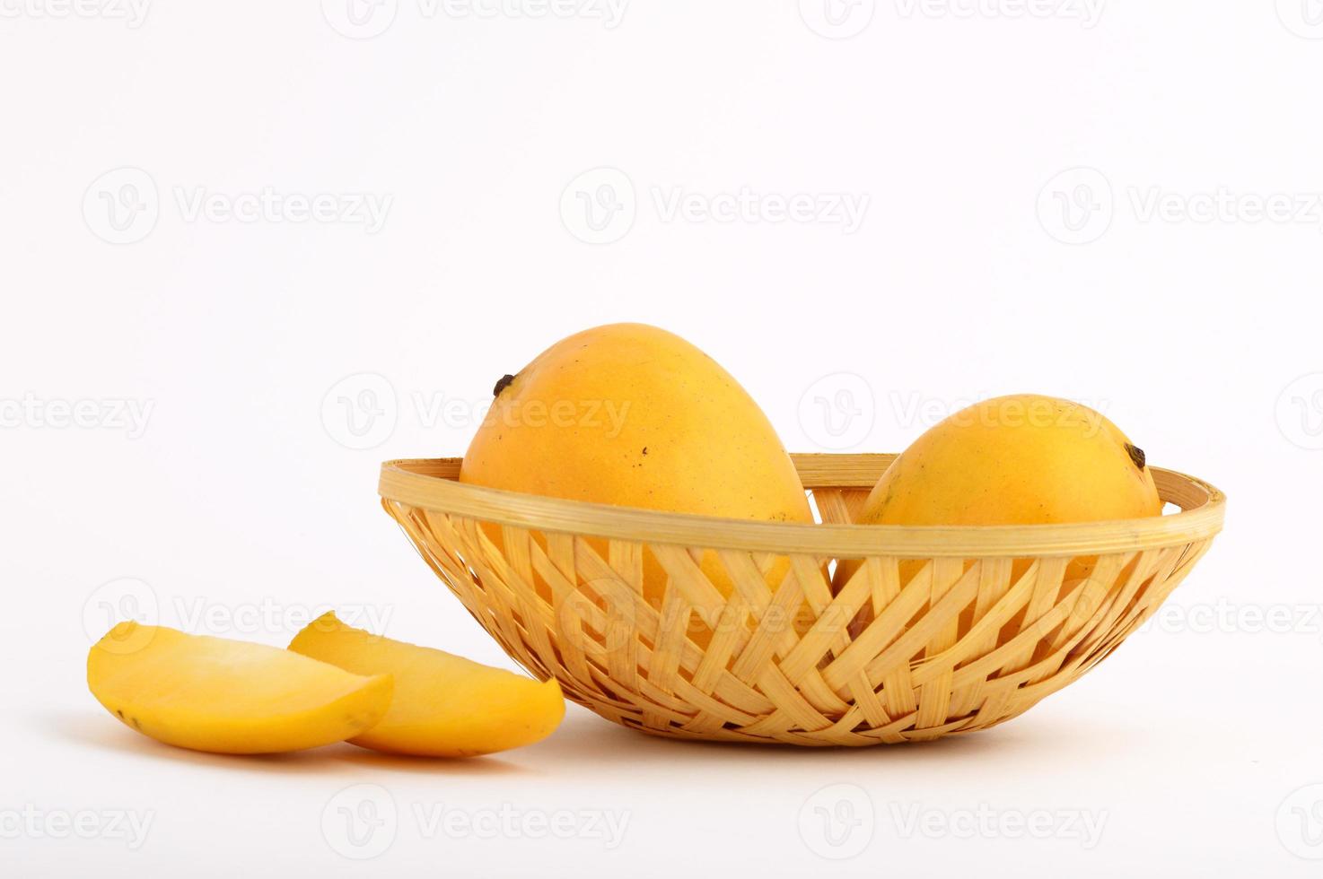 Frutto di mango in cesto con fetta su sfondo bianco foto