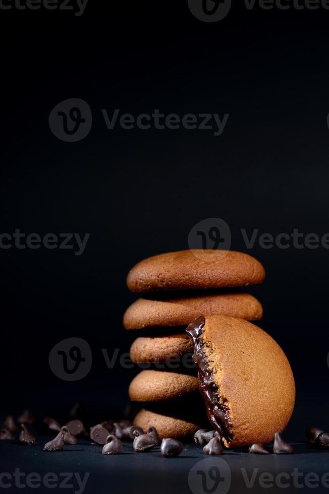 biscotti - pila di deliziosi biscotti alla crema ripieni di crema al cioccolato su sfondo nero foto