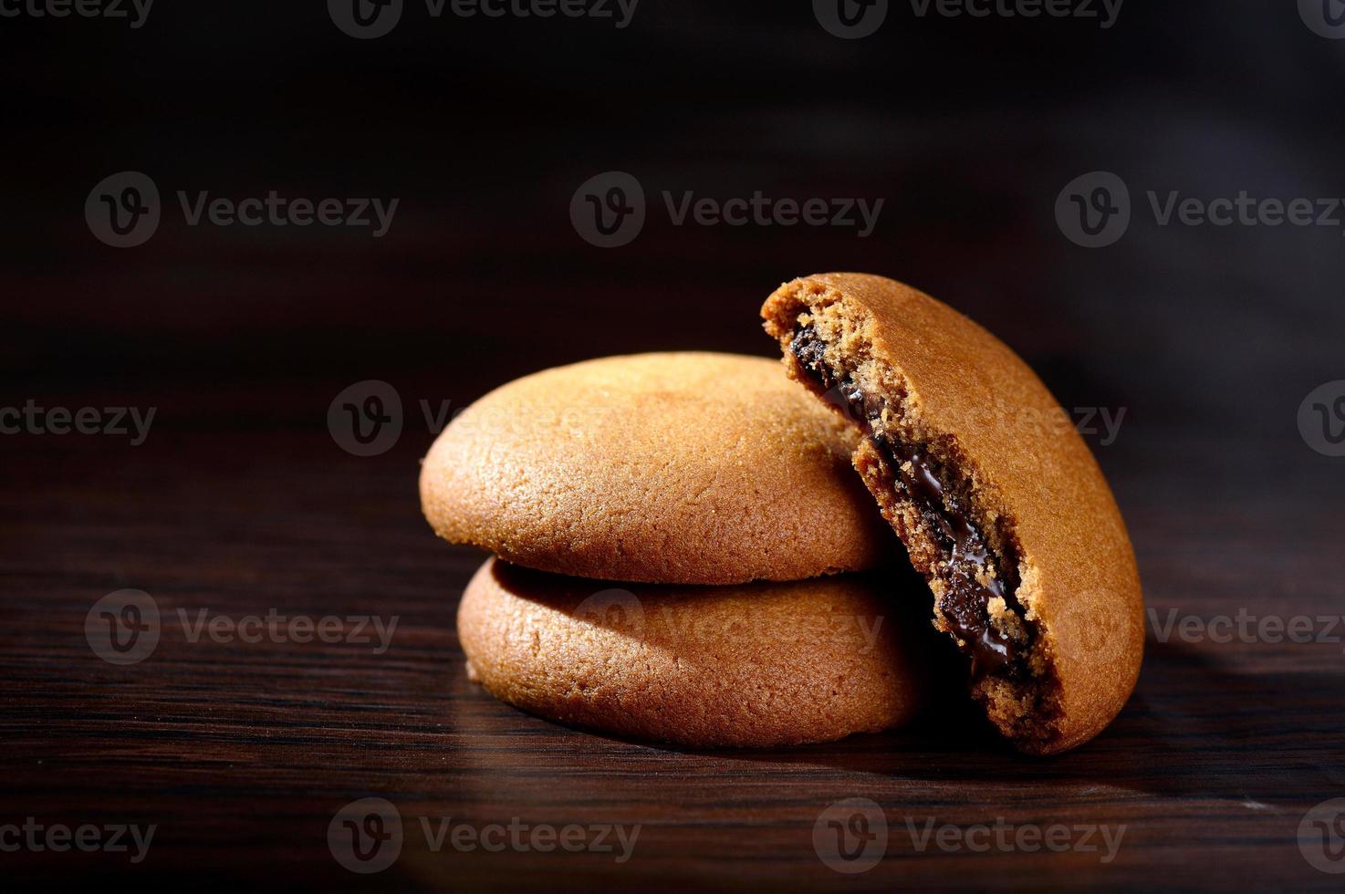 biscotti ripieni di crema al cioccolato. biscotti alla crema di cioccolato. biscotti al cioccolato marrone con ripieno di crema su sfondo nero. foto