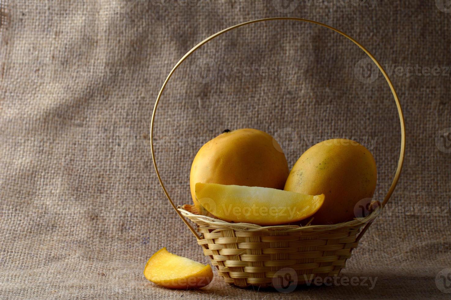 frutta di mango nel cesto su sfondo di tela di sacco foto