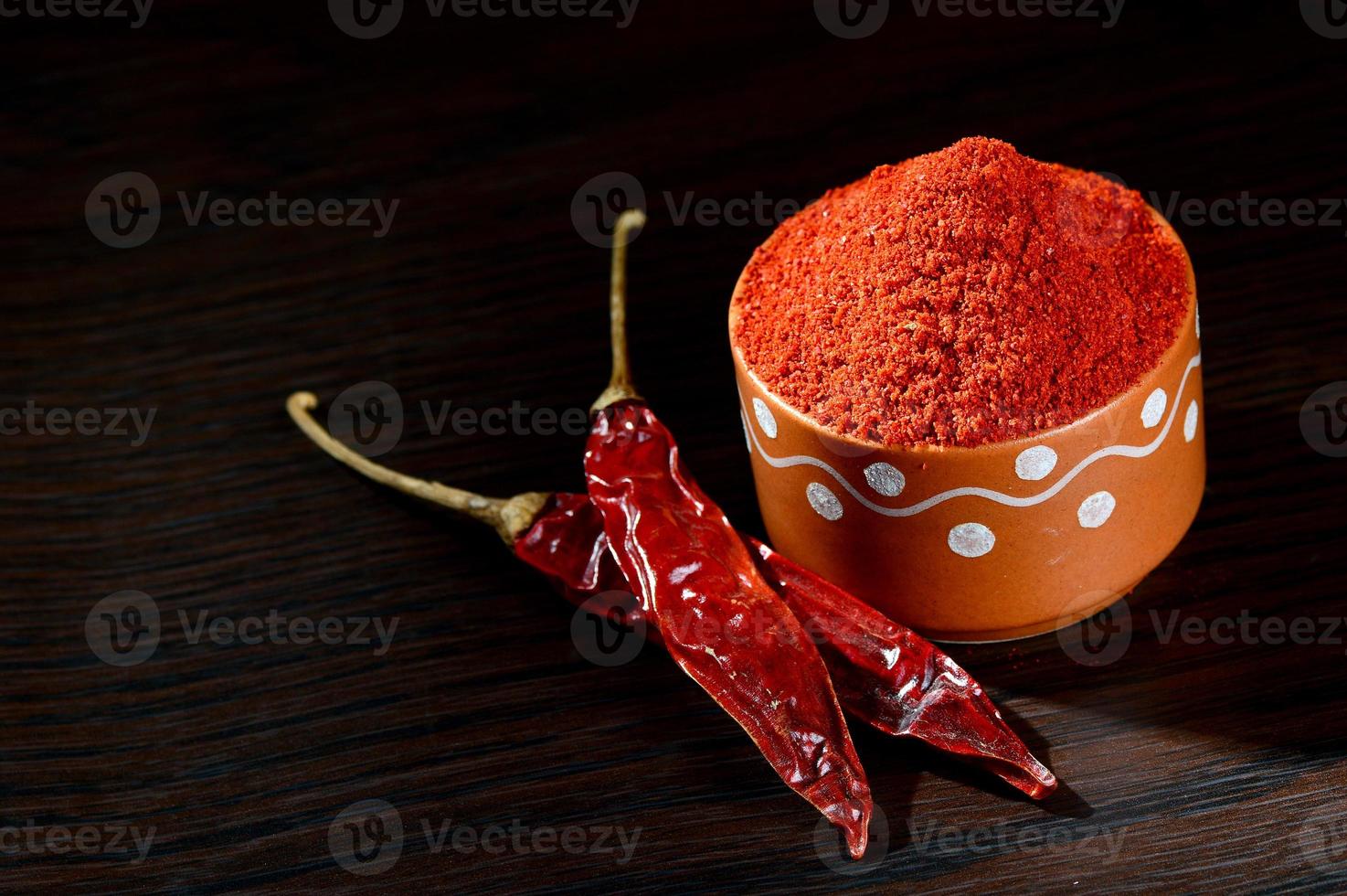 polvere fredda in vaso di argilla con peperoncino rosso, peperoncino secco su fondo di legno wooden foto