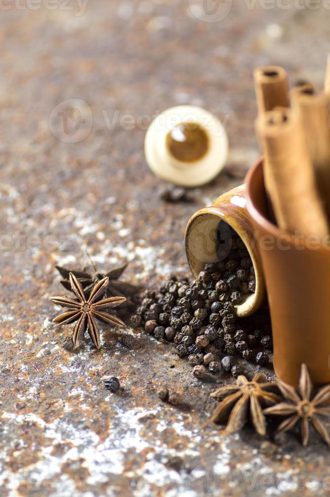 spezie ed erbe aromatiche. cibo e ingredienti della cucina. bastoncini di cannella, stelle di anice, grani di pepe nero su sfondo strutturato foto