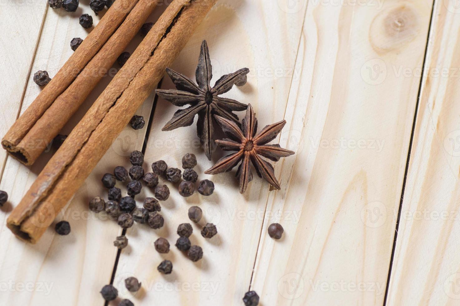 spezie ed erbe aromatiche. cibo e ingredienti della cucina. bastoncini di cannella, stelle di anice e grani di pepe nero su uno sfondo di legno. foto