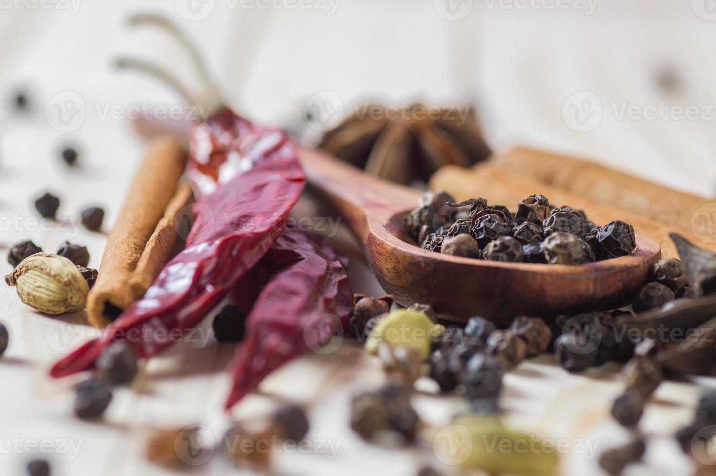 spezie ed erbe aromatiche. cibo e ingredienti della cucina. bastoncini di cannella, stelle di anice, grani di pepe nero, peperoncino, cardamomo e chiodi di garofano su uno sfondo di legno foto