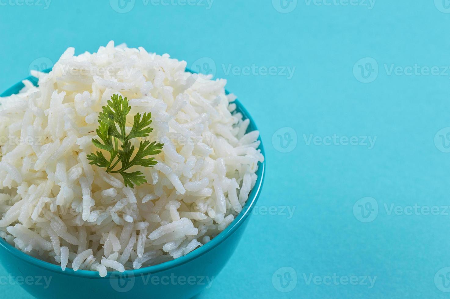 riso basmati bianco cotto con coriandolo in una ciotola blu su sfondo blu foto