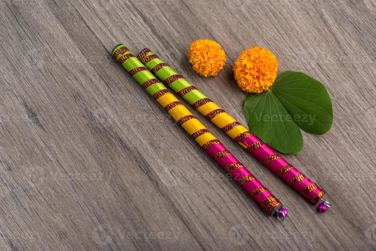 festival indiano dussehra e navratri, che mostra foglie dorate e fiori di calendula con bastoncini dandiya su uno sfondo di legno foto