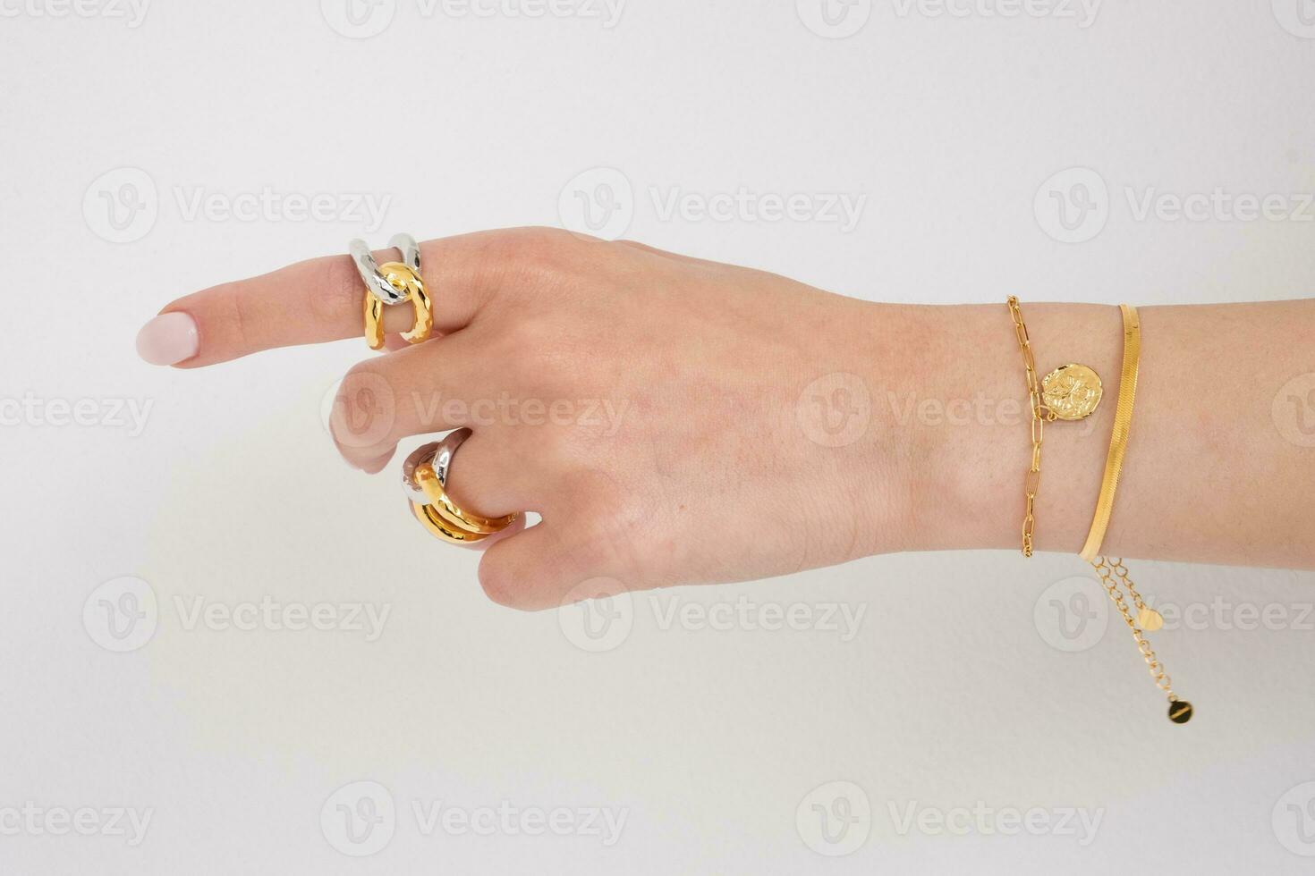 donna mano indossare farfalla e serpente catena bracciali e interbloccata d'oro e argento anelli impostato contro un' bianca sfondo. bellissimo San Valentino regalo. foto