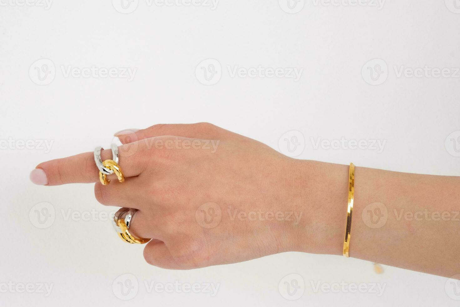 donna mano indossare d'oro serpente catena braccialetto e interbloccata d'oro e argento anelli impostato contro un' bianca sfondo. bellissimo San Valentino regalo. foto