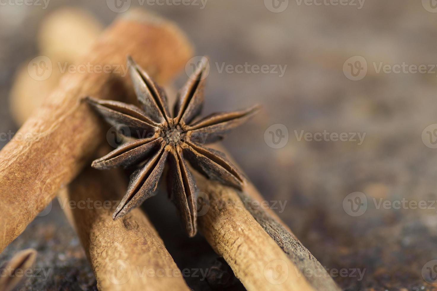 bastoncini di cannella, stelle di anice e grani di pepe nero su sfondo strutturato foto