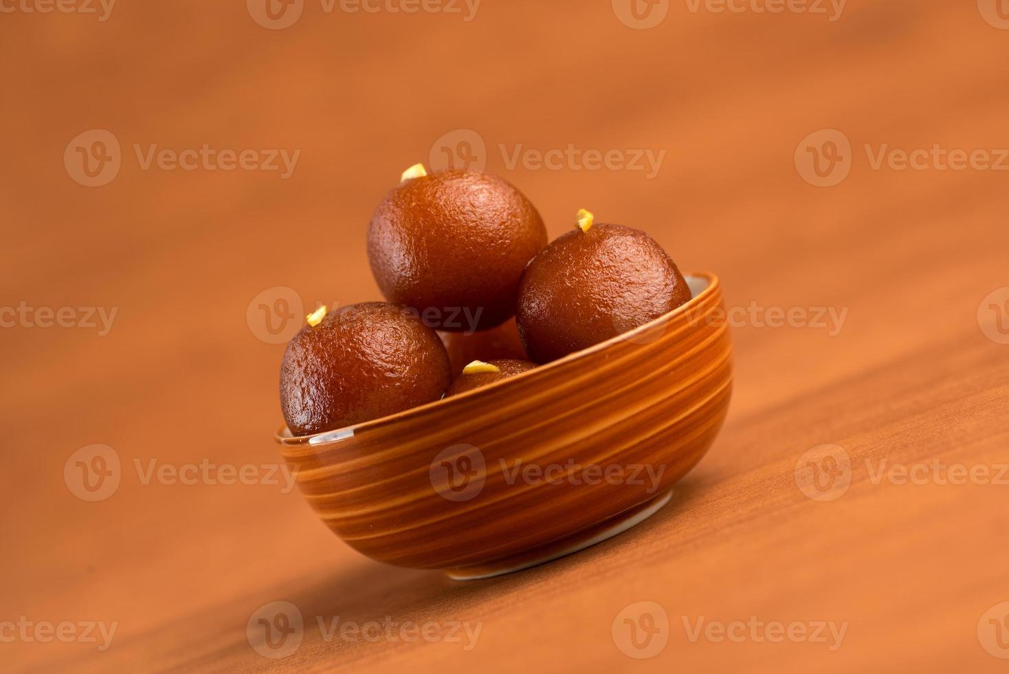 gulab jamun in una ciotola su sfondo di legno. dessert indiano o piatto dolce. foto