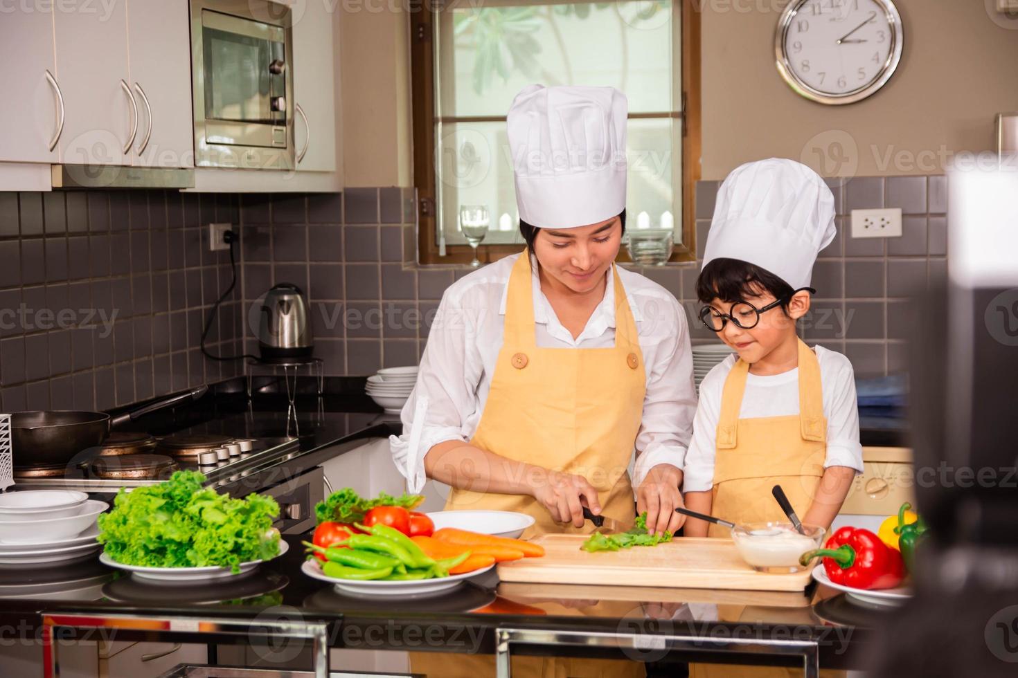 donna asiatica con figlio che cucina cibo in cucina a casa foto