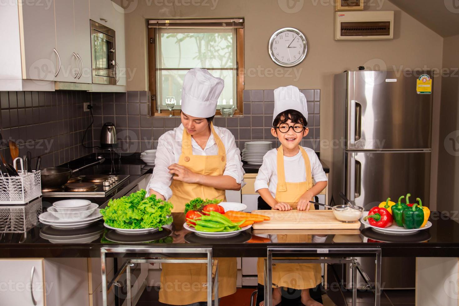 donna asiatica con figlio che cucina cibo in cucina a casa foto