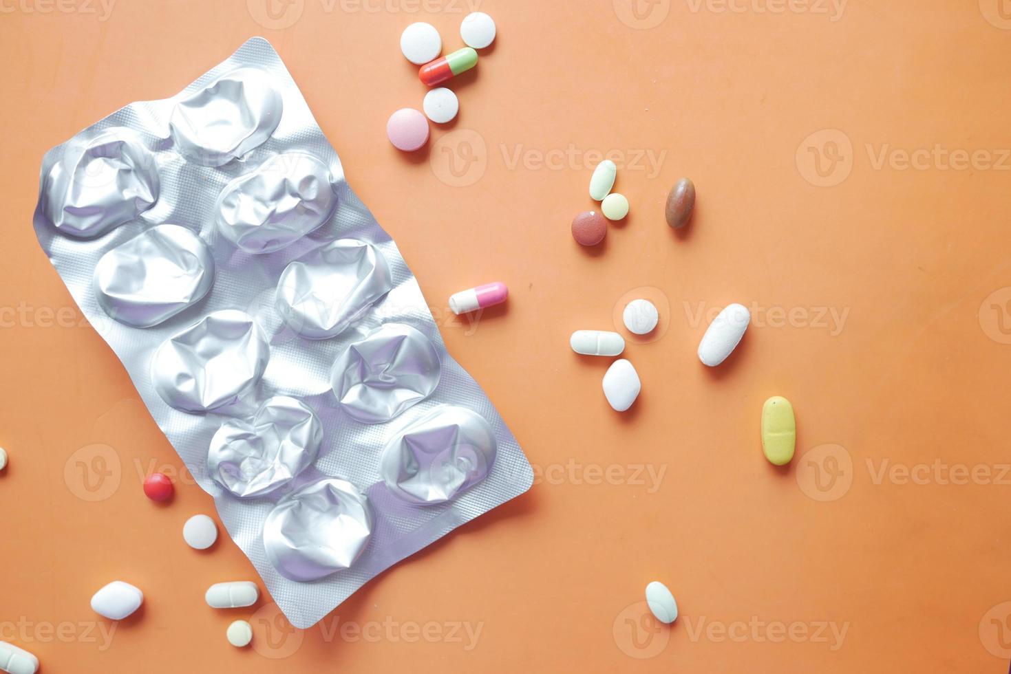 primo piano di pillole di blister e pillole mediche su sfondo arancione foto