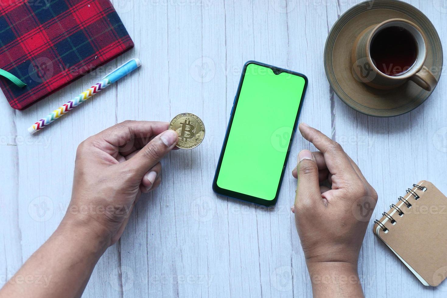 dhaka bangladesh 23 maggio 2021, in possesso di bitcoin d'oro e utilizzando lo smartphone foto