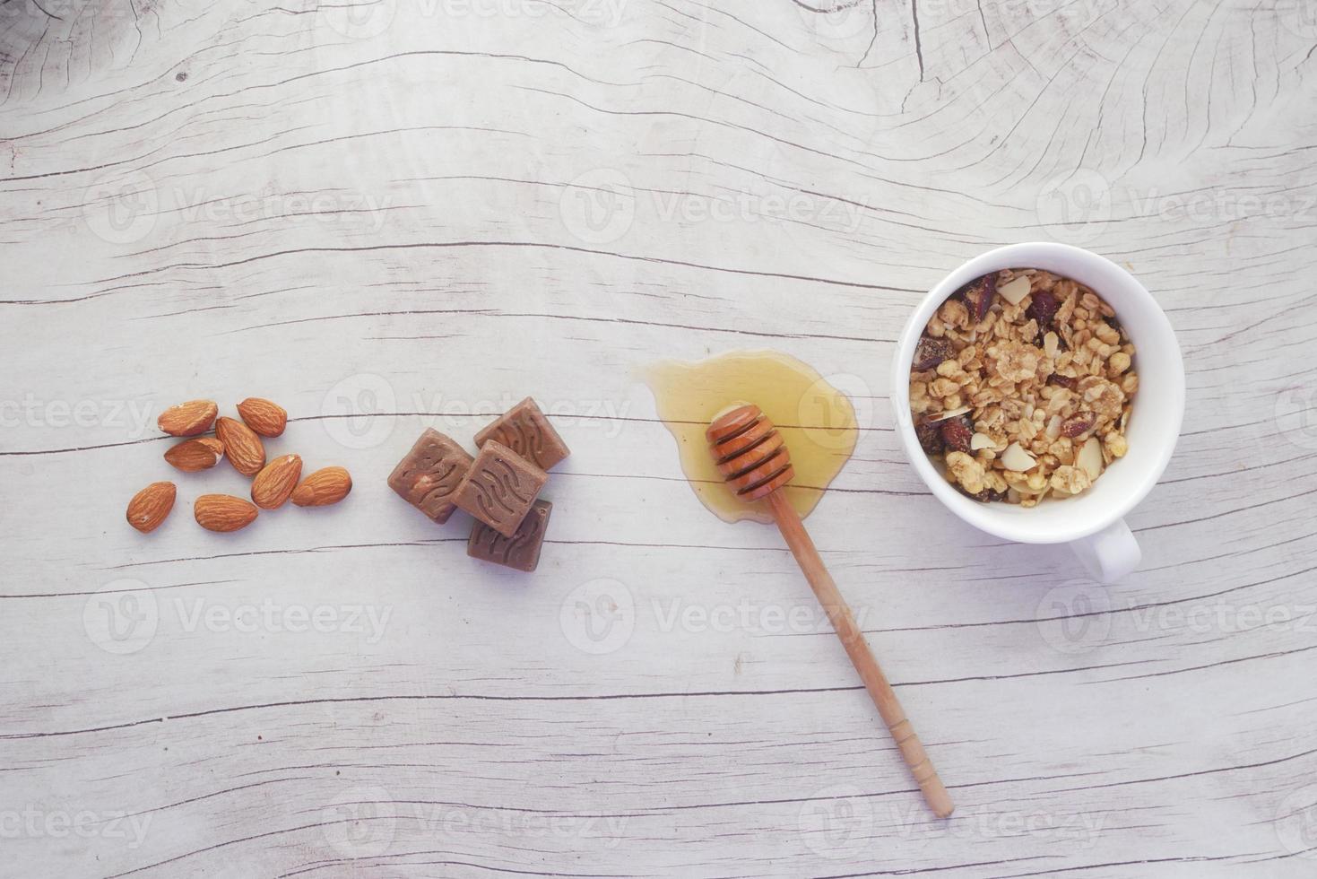 colazione di cereali in una ciotola, mandorla. cioccolato e miele in tavola foto