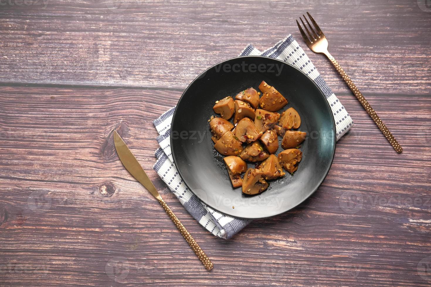 funghi saltati con aglio e prezzemolo su un piatto nero su sfondo bianco foto