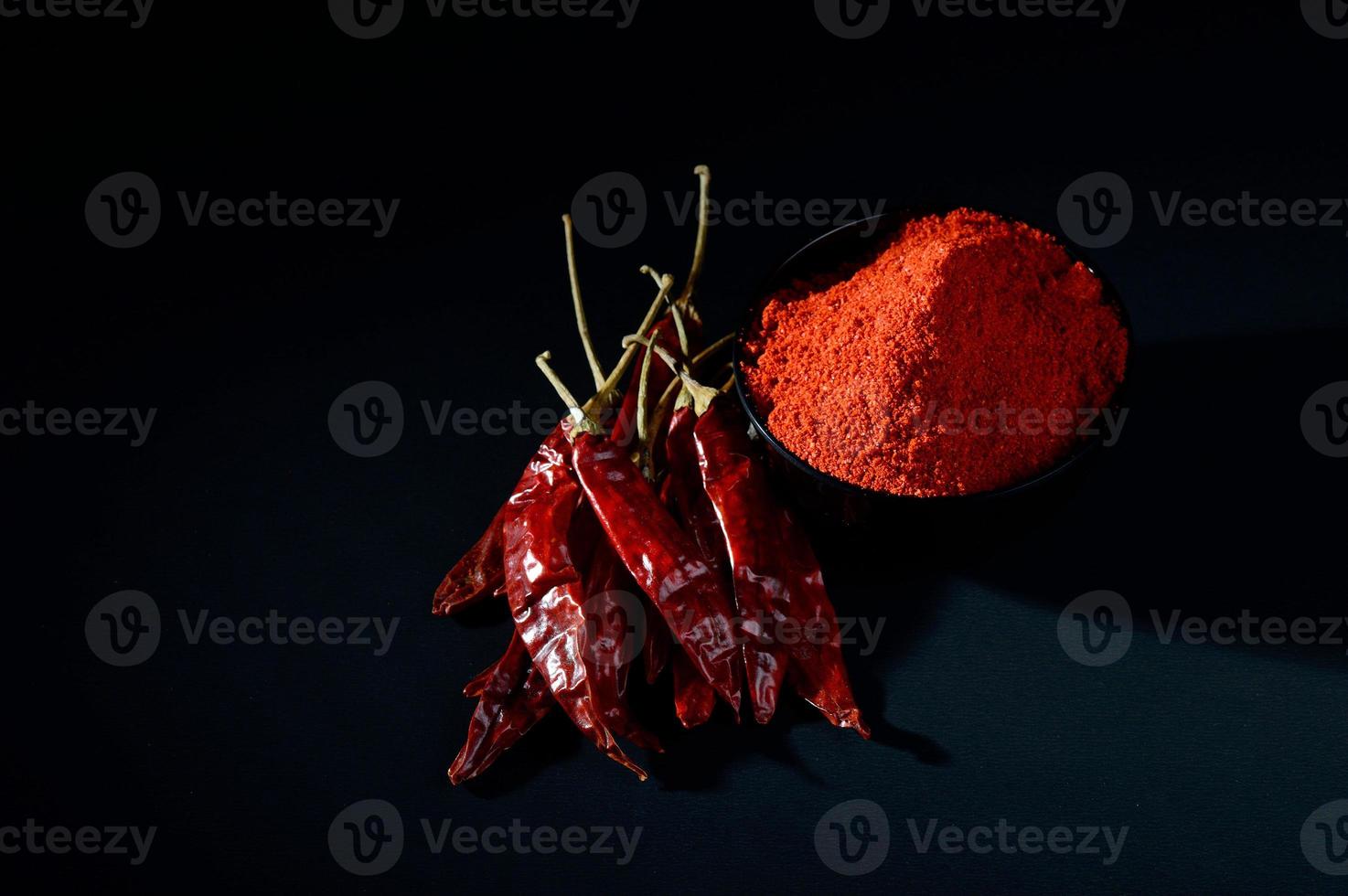 polvere fredda in una ciotola nera con peperoncino rosso, peperoncino secco su sfondo nero foto