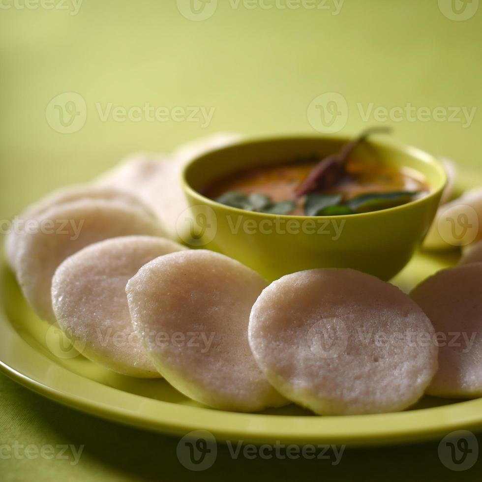 idli con sambar in una ciotola su sfondo verde, piatto indiano cibo preferito dell'India meridionale rava idli o semolino pigramente o rava pigramente, servito con sambar e chutney di cocco verde. foto