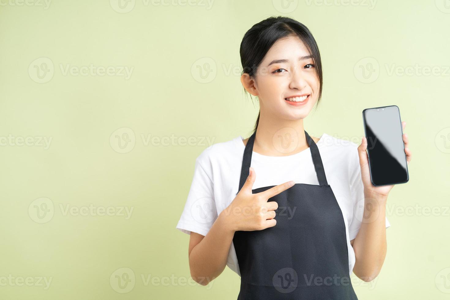 cameriera asiatica che tiene il suo telefono con una faccia allegra foto