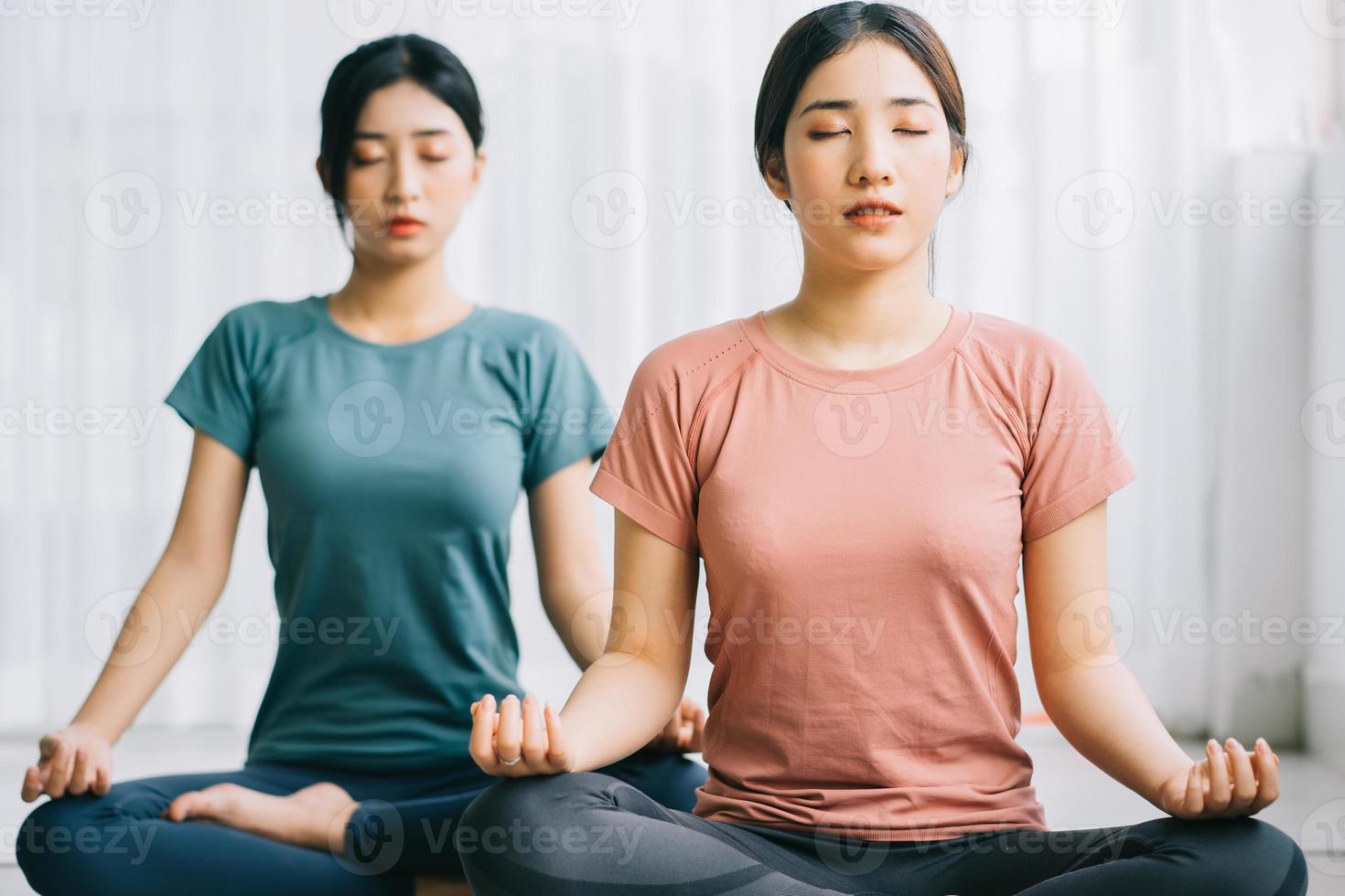 due donne asiatiche praticano la meditazione a casa foto