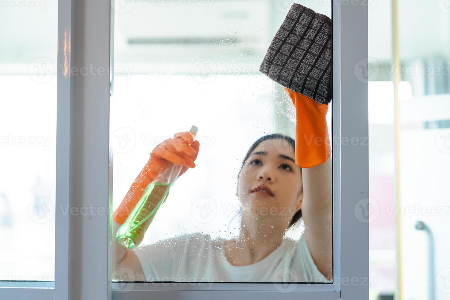 bella donna asiatica che pulisce la porta di vetro della camera da letto? foto