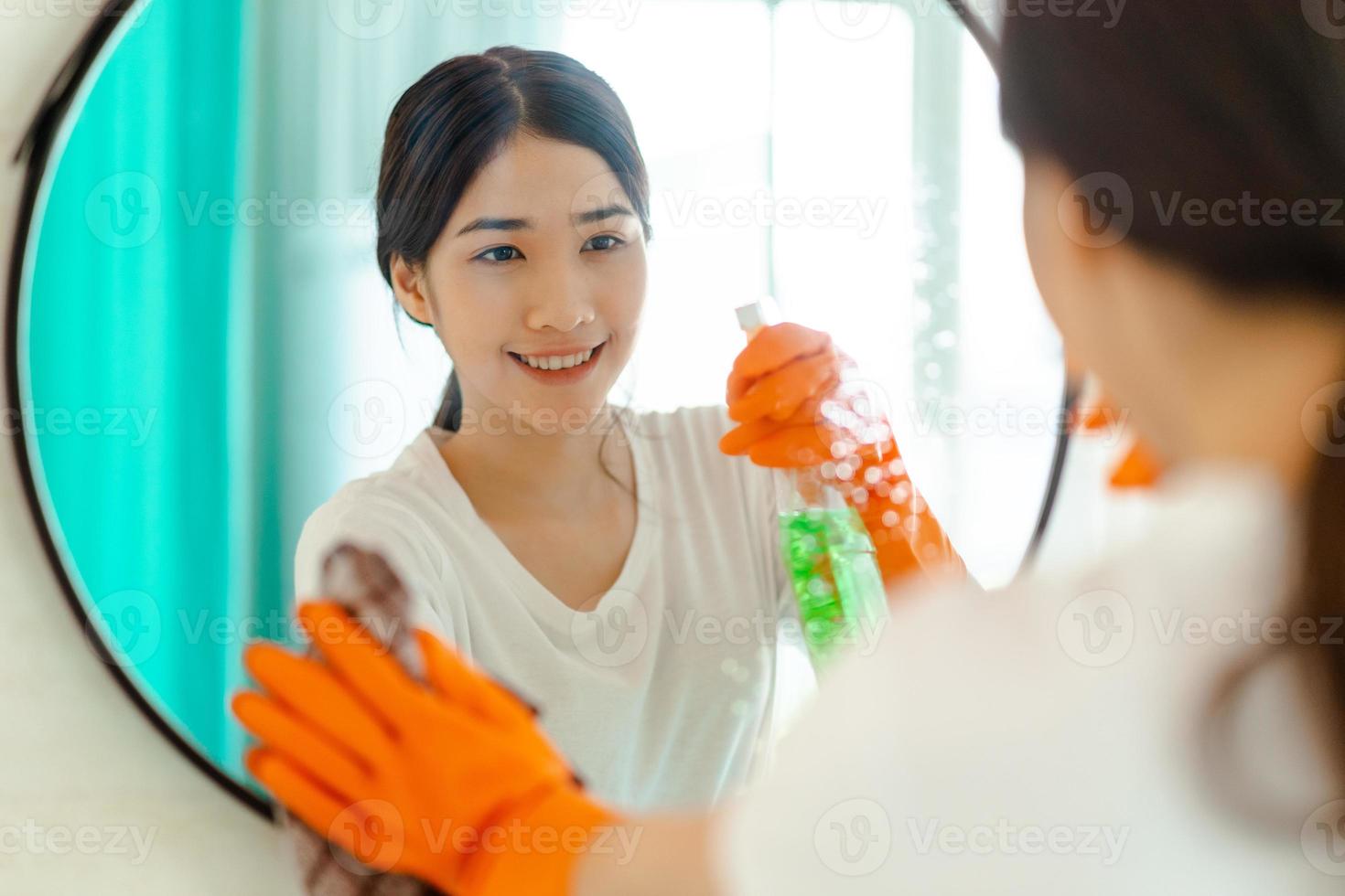 bella donna asiatica che pulisce lo specchio in bagno? foto