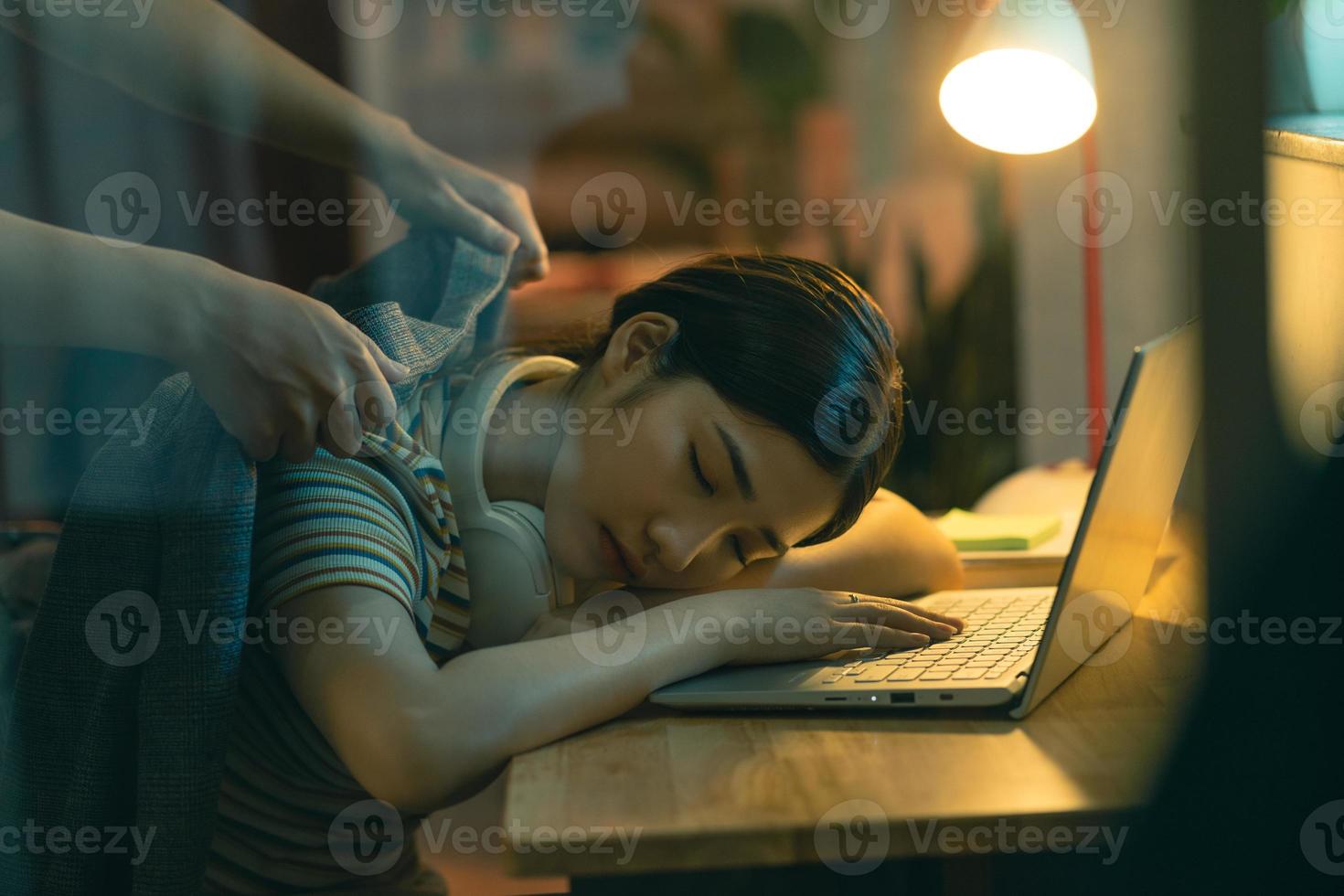 la donna asiatica si sta addormentando mentre lavora di notte, il marito sta coprendo la moglie addormentata foto