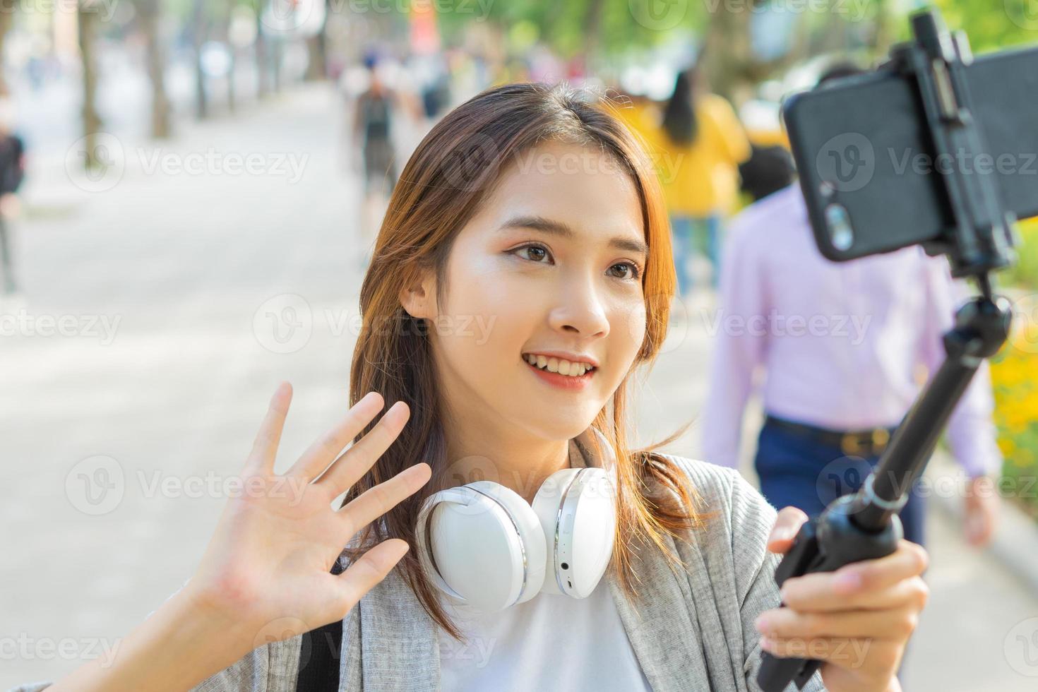 donna asiatica che registra video per strada ad hanoi, vietnam foto