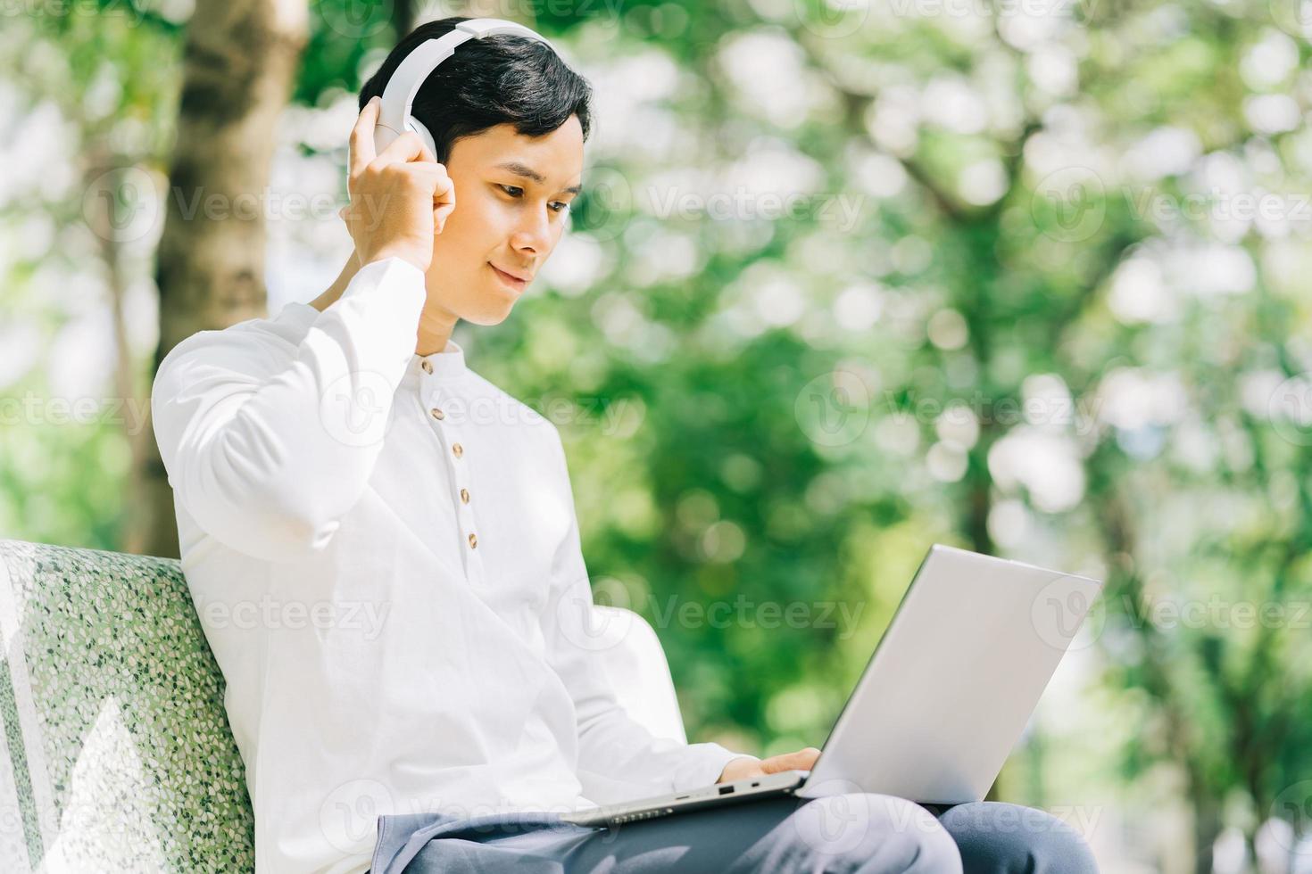 bell'uomo asiatico seduto usando il laptop per lavorare al parco? foto