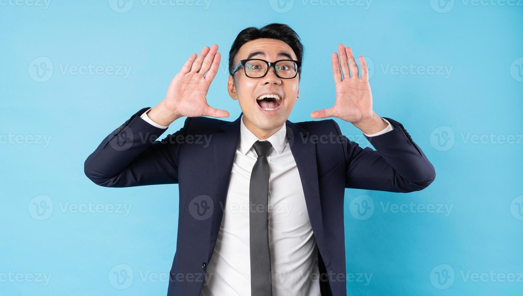 uomo d'affari asiatico che indossa tuta gridando su sfondo blu foto