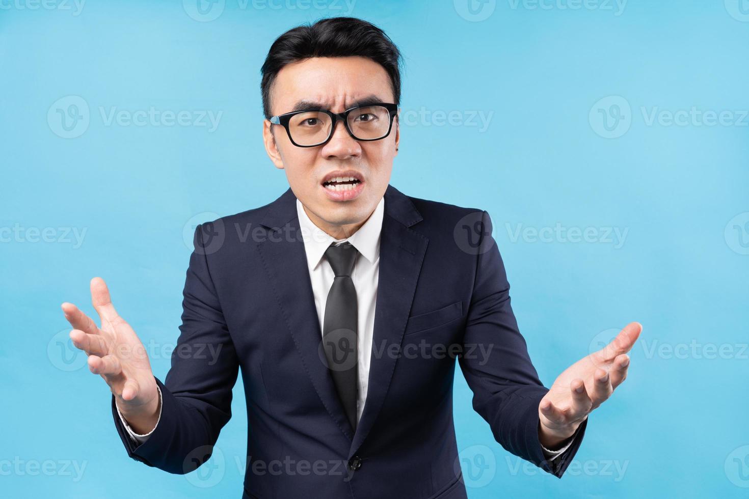 uomo d'affari asiatico che indossa un abito arrabbiato su sfondo blu blue foto