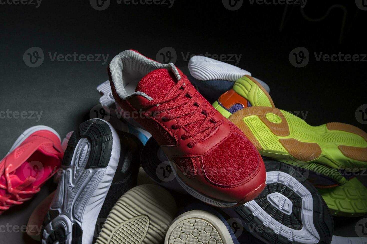 multicolore scarpe da ginnastica siamo impilati nel un' mucchio su un' grigio sfondo. sport scarpe. foto