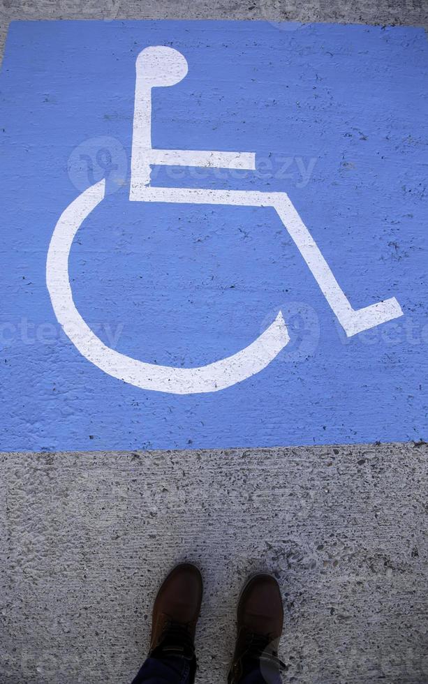 piedi su un cartello per disabili sull'asfalto foto