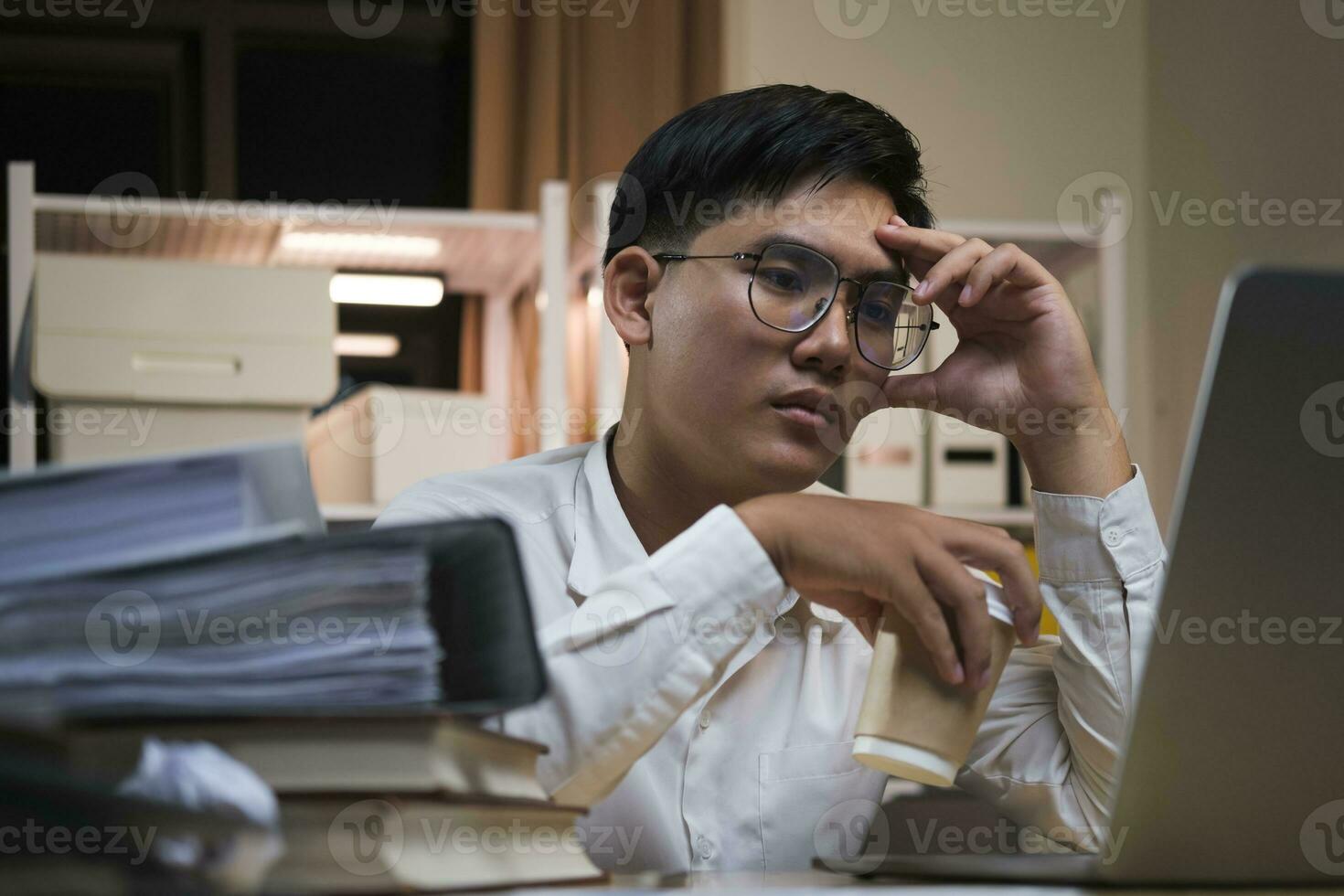 asiatico giovane stanco personale uomo d'affari utilizzando del desktop computer avendo lavorare troppo progetto durante la notte nel ufficio. foto