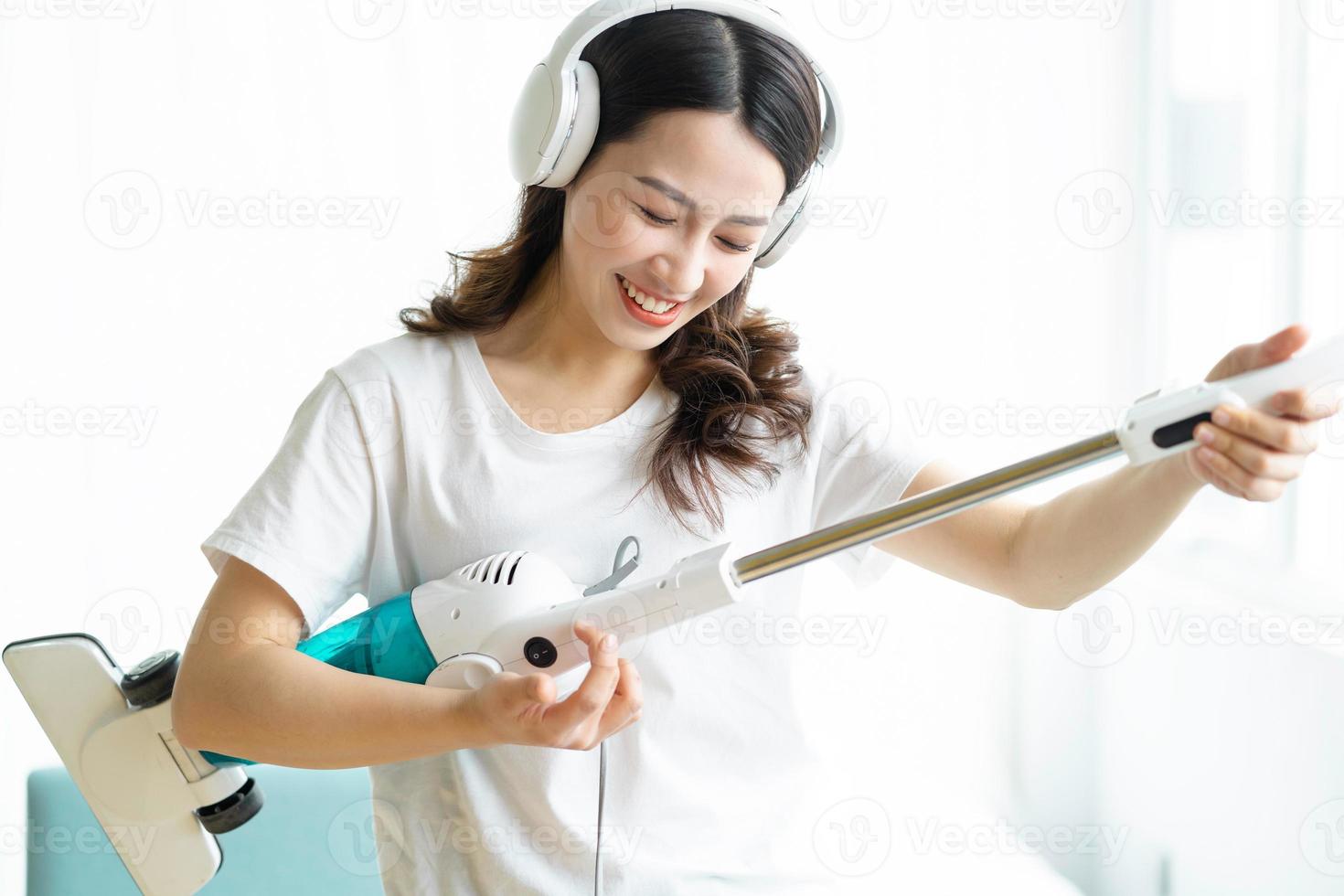 donna asiatica che ascolta musica e balla con un aspirapolvere foto